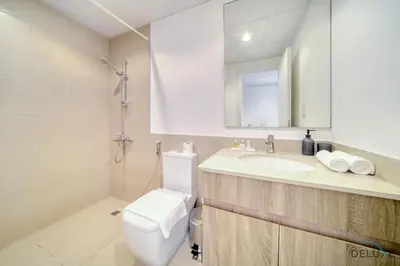 a bathroom with a toilet and a sink and a mirror at Immaculate 1BR at UNA Town Square Dubailand by Deluxe Holiday Homes in Dubai
