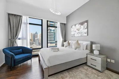 a bedroom with a large bed and a blue chair at StoneTree - Chic & Modern 1BR in Dubai