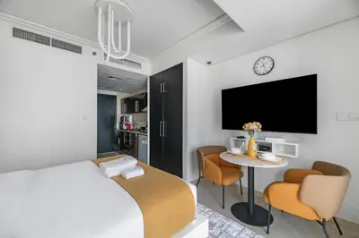 a bedroom with a bed and a table with chairs at StoneTree - Modern Furnished Studio in Dubai