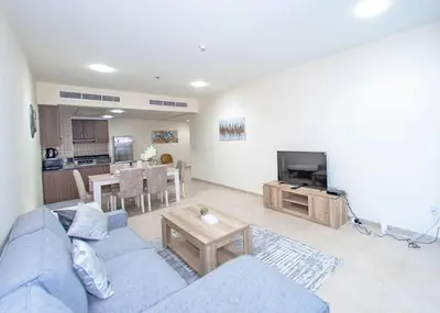 a living room with a blue couch and a tv at StoneTree - Near Tram - Furnished 1BR in Dubai