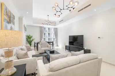 a living room with white furniture and a chandelier at Heaven Crest Vacation Homes Downtown - Studio and 1 Bedroom Suites 2 minute walk to Dubai Mall and Burj Khalifa in Dubai