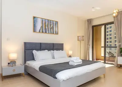 a bedroom with a large white bed with a picture on the wall at StoneTree - Studio Apartment Near The Beach in Dubai