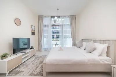 a white bedroom with a large bed and a television at StoneTree - Furnished Studio in Golf Promenade 3A in Dubai