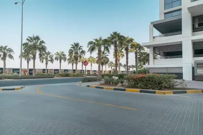 an empty street in front of a building with palm trees at StoneTree - Furnished Studio in Golf Promenade 3A in Dubai