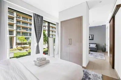 a bedroom with a white bed and a large window at StoneTree - Cozy 1 BR in Sobha Hartland Greens 1 in Dubai