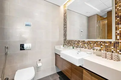 a bathroom with two sinks and a mirror at StoneTree - Cozy 1 BR in Sobha Hartland Greens 1 in Dubai