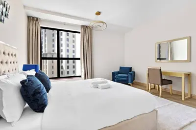 a bedroom with a large white bed with blue pillows at StoneTree - Near Beach - Furnished 1BR with Partial Sea View in Dubai