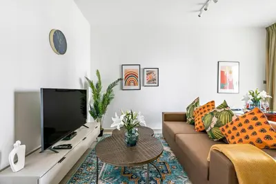 a living room with a couch and a tv at StoneTree - Furnished 1 BR Apartment Near to Tram in Dubai