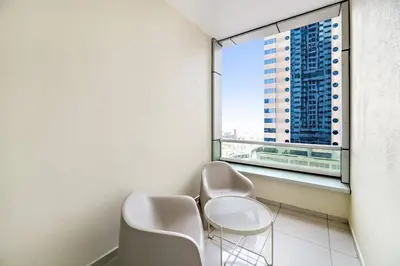 two chairs and a table in a room with a window at StoneTree - Furnished 1 BR Apartment Near to Tram in Dubai