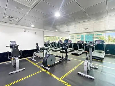 a gym with rows of exercise bikes and treadmills at StoneTree - Furnished 1 BR Apartment Near to Tram in Dubai
