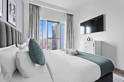 a white bedroom with a large bed and a large window at StoneTree - New stylish 1 BR Apartment in JLT in Dubai