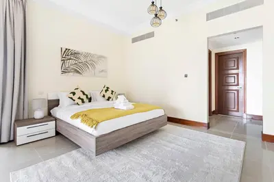 a white bedroom with a large bed and a chandelier at StoneTree - Luxurious 2 BR Apartment in Palm Jumeirah in Dubai