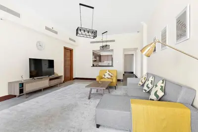 a living room with a couch and a tv at StoneTree - Luxurious 2 BR Apartment in Palm Jumeirah in Dubai