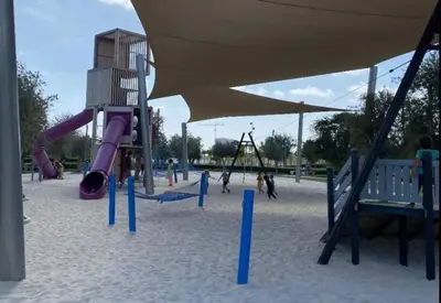 a playground with a purple slide and swings at 2bedroom apartment Dubai Hills in Dubai
