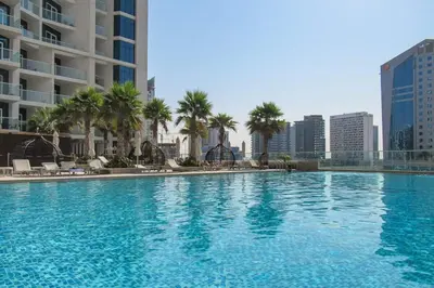 a large swimming pool with palm trees and buildings at Frank Porter - Damac Prive B in Dubai