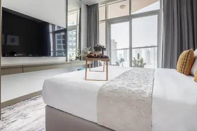 a white bedroom with a large bed and a large window at Frank Porter - Damac Prive B in Dubai