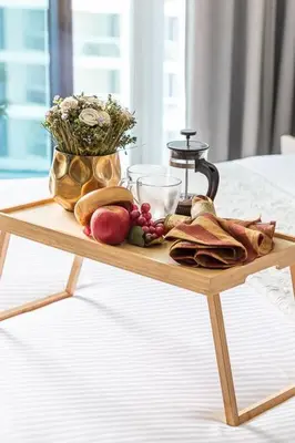 a wooden tray with fruit and a candle on a bed at Frank Porter - Damac Prive B in Dubai