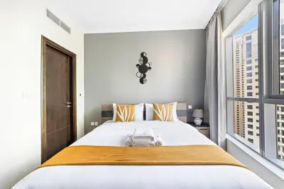 a bedroom with a large white bed and a window at StoneTree - Near JBR Beach - Prime Location in Dubai