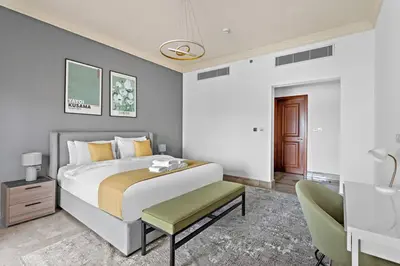 a bedroom with a large bed and a chair at StoneTree - Elegant 2BR with 1 Maids Room in Dubai