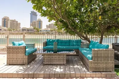 a blue couch and two chairs under a tree at 6 Bedroom Modern Luxury Villa In Palm Jumeirah in Dubai