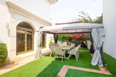 a table and chairs under an umbrella on a lawn at 6 Bedroom Modern Luxury Villa In Palm Jumeirah in Dubai