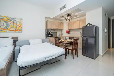 a living room with a bed and a kitchen at Bright & Elegant Studio Balcony Speedy Wi-Fi in Dubai