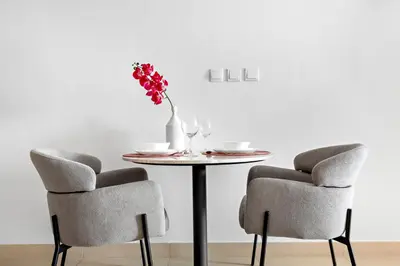 a table with two chairs and a vase of flowers on it at StoneTree - Modern Stylish Studio in JLT in Dubai