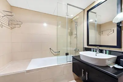 a bathroom with a sink and a glass shower at StoneTree - Modern Stylish Studio in JLT in Dubai