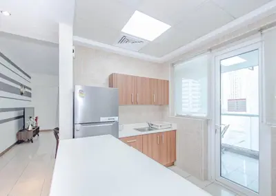 a white kitchen with a refrigerator and a window at StoneTree - Spacious 1BR - Best Location for Tourist in Dubai