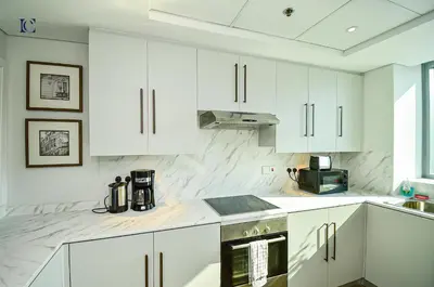 a white kitchen with white cabinets and a stove at Luxury Escapes - Newly furnished 1BR Apartment - 8 BLVD WALK DOWNTOWN in Dubai
