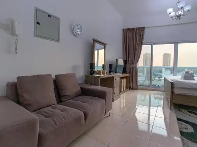 a living room with a brown couch and a television at StoneTree - Furnished Studio in Peaceful Location in Dubai