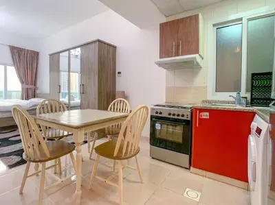 a kitchen with a table and chairs and a red refrigerator at StoneTree - Furnished Studio in Peaceful Location in Dubai