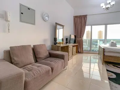 a living room with a couch and a television at StoneTree - Furnished Studio in Peaceful Location in Dubai