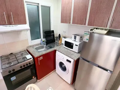 a small kitchen with a refrigerator and a sink at StoneTree - Furnished Studio in Peaceful Location in Dubai