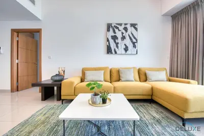 a living room with a yellow couch and a table at Exquisite 3BR at Ocean Heights Dubai Marina by Deluxe Holiday Homes in Dubai