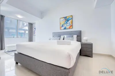 a white bedroom with a large bed and a window at Exquisite 3BR at Ocean Heights Dubai Marina by Deluxe Holiday Homes in Dubai
