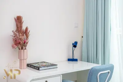 a white desk with a vase of flowers on it at Marco Polo - Relax in a modern 1BR in Dubai Marina in Dubai