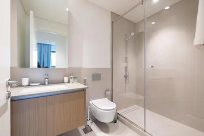 a bathroom with a shower and a toilet and a sink at Modern 1 Bedroom Apartment I Creek Beach I Surf in Dubai