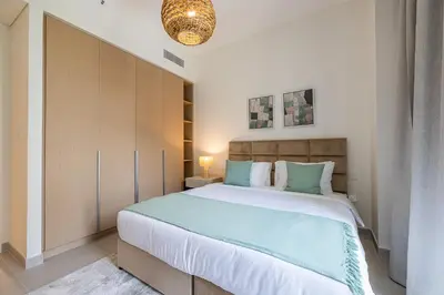a bedroom with a large bed with a wooden cabinet at Modern 1 Bedroom Apartment I Creek Beach I Surf in Dubai