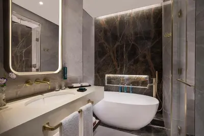 a bathroom with a tub and a sink and a mirror at Embassy Suites By Hilton Dubai Business Bay in Dubai