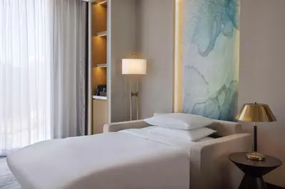 a bedroom with a white bed and a lamp at Embassy Suites By Hilton Dubai Business Bay in Dubai