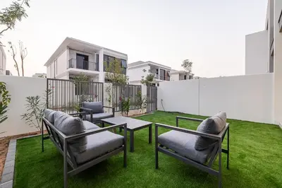 a patio with chairs and tables on the grass at Townhouse with Garden I Tilal Al Ghaf I Elan B in Dubai