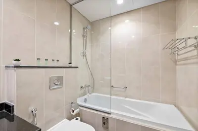 a bathroom with a tub and a toilet and a sink at StoneTree - Stylish Studio Apartment in Damac Hills in Dubai