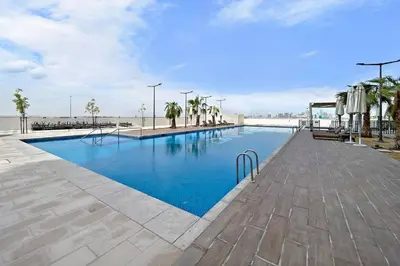 a swimming pool with blue water next to a beach at StoneTree - Stylish Studio Apartment in Damac Hills in Dubai
