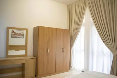 a bedroom with a wooden cabinet and a window at Your Silicon Oasis Escape-1BHK in Dubai