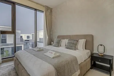 a bedroom with a large bed with a large window at Brand New Luxurious 4BR & Maid Room Townhouse in Dubail Hill Estate in Dubai