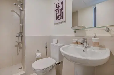 a white bathroom with a toilet and a sink at Brand New Luxurious 4BR & Maid Room Townhouse in Dubail Hill Estate in Dubai