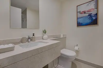 a white bathroom with a toilet and a sink at Brand New Luxurious 4BR & Maid Room Townhouse in Dubail Hill Estate in Dubai