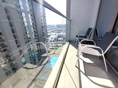 a balcony with chairs and a swimming pool on a building at New 1 bedroom in Sobha - Community View in Dubai