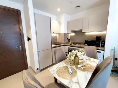 a dining room table with chairs and a kitchen at New 1 bedroom in Sobha - Community View in Dubai